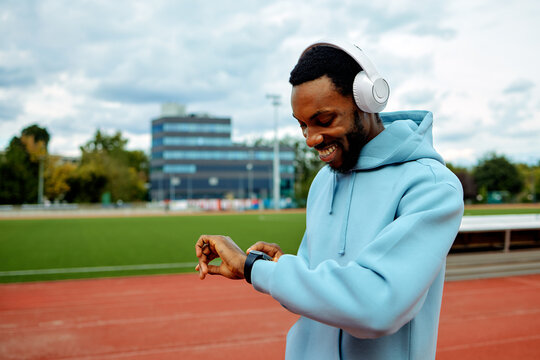 Smiling man checking smartwatch on running track