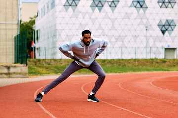 Athlete stretching leg muscles on a running track