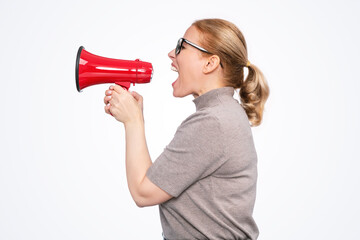 Side view of a woman shouting into a red megaphone, wearing glasses and casual clothes, isolated on...