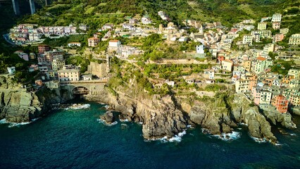 A unique drone view of the coastline of Riomaggiore, Italy. This shot highlights the train station area and the famous coastal path carved into the rocks above the sea