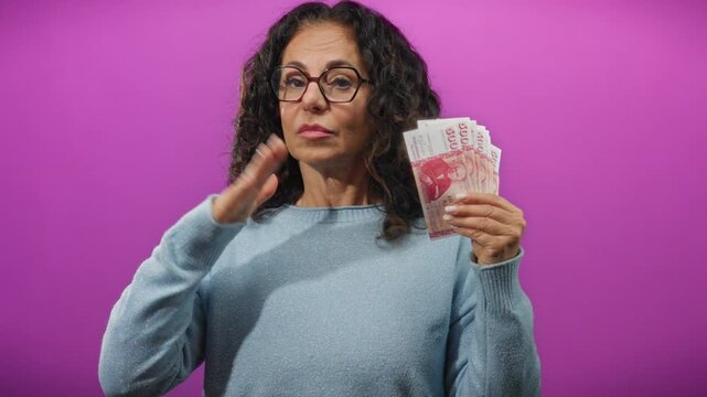 Woman holding icelandic krona banknotes against a vibrant purple background, symbolizing financial commitment or promise.