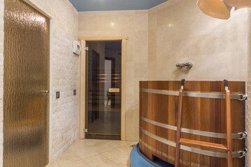 A bright room of the spa center with a glass door to the sauna. Cedar barrel for spa treatments.