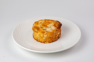Golden almond-topped pastry on textured white plate