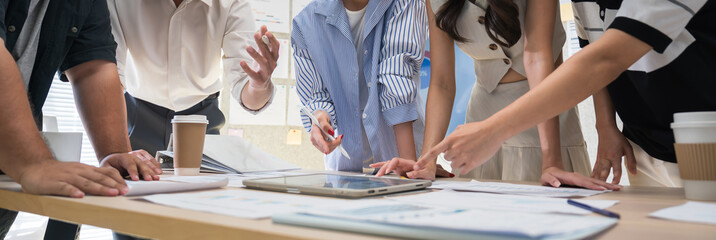 Group of professionals analyzing data charts during a business meeting in a modern office, collaborating on strategies and reviewing financial or project performance.