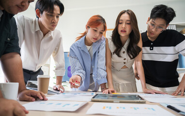 Business Asian team in office meeting working with documents and laptops on table, brainstorming creative ideas and planning strategies for a new business venture.