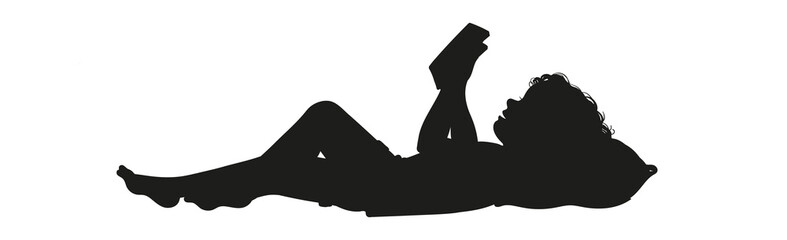 Silhouette of a person reading a book while lying down