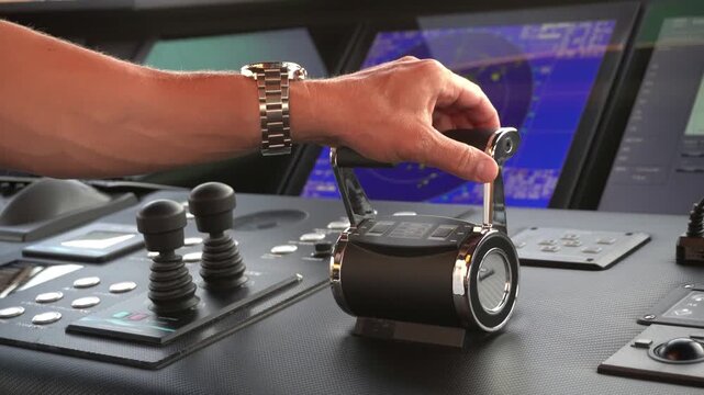 Close-up of a captain&rsquo;s hand operating twin engine throttles on a yacht bridge &mdash; one lever set forward and the other in reverse. Maritime vessel maneuvering with radar and navigation displays