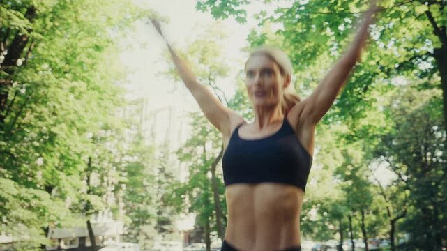 Fit woman doing jumping exercises with resistance band outdoors