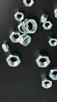 Metal hex nuts, fastening concept, industrial application, mechanical engineering context - various steel nuts with blue nylon inserts on black surface, illustrating construction hardware and precisio