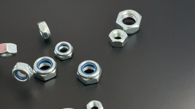 Metal hex nuts, fastening concept, industrial application, mechanical engineering context - various steel nuts with blue nylon inserts on black surface, illustrating construction hardware and precisio