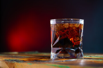 Whiskey and cola in a glass glass with ice on the table