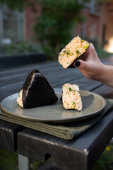 Japanese street food, woman holding fresh rice ball onigiri with nori, summertime.