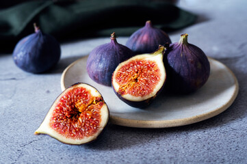 Fresh ripe figs served on plate, whole and sliced fruits.
