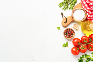 Spices, herbs and vegetables with olive oil on white kitchen table.