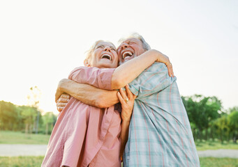 Happy active senior couple having fun talking and hugging in park outdoors