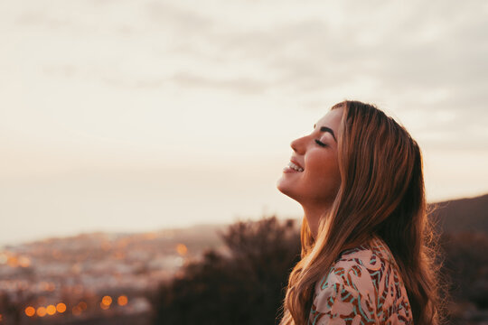 Portrait close up of face of one young beautiful woman smiling with closed eyes enjoying freedom sensation emotion. Teen cheerful young female outdoors having fun. - Powered by Adobe