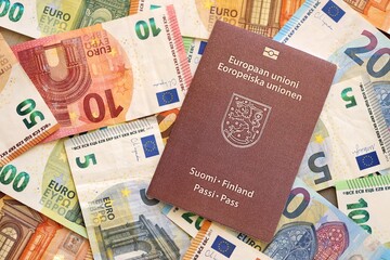 Finland passport lies on big amount of euro money banknotes. Rich life and travel in Europe