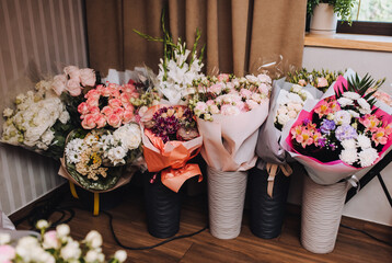 A lot of gift-wrapped flowers and bouquets in vases stand in the room at a wedding or birthday celebration.