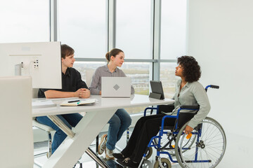 Teamwork brainstorm. Diverse multiracial colleagues woman in chair for people with disability working together. Group of people sitting in creative office discussing business. Young professional team