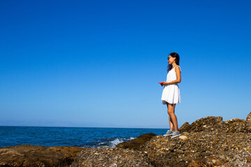 Woman Standing Alone on Coastal Rocks Gazing at the Ocean Horizon