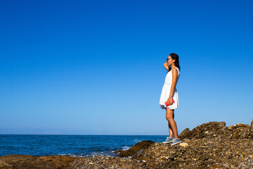 Woman Standing Alone on Coastal Rocks Gazing at the Ocean Horizon