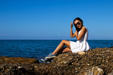 Stylish Woman Posing on Coastal Rocks by the Sea on a Sunny Day
