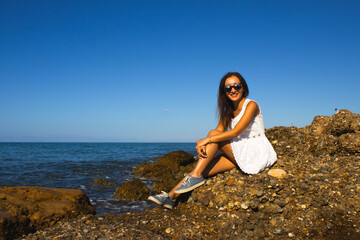 Relaxed Woman Sitting on Coastal Rocks Gazing at the Ocean
