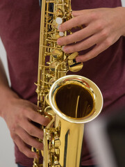 Human hand holding playing a saxophone close up with another saxophone in the background during musiclessons