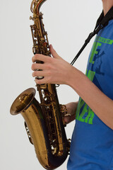 Human hand holding playing a saxophone close up with another saxophone in the background during musiclessons