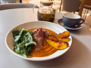 Restaurant dish with duck breast, spinach, grilled peach and puree on plate. Modern cuisine, healthy eating, and creative food presentation.