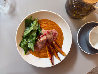 Top view of restaurant dish with duck breast, spinach, grilled peach, and puree. Modern cuisine, healthy nutrition, and creative dining experience.