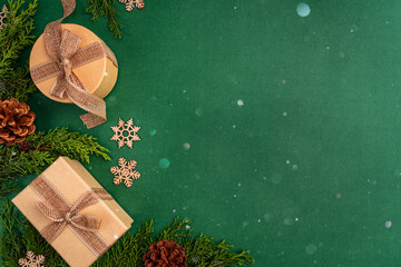 Natural holiday flat lay with kraft-wrapped gifts, pine cones, greenery, and wooden snowflakes on a...