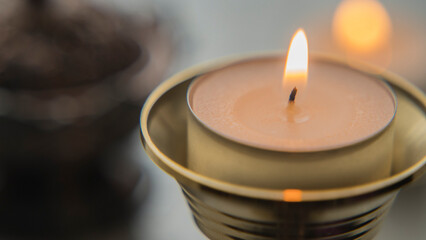 A lit candle in a candlestick in the foreground close-up