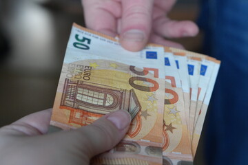 Close-up of a Financial Transaction: One Person Handing Over Multiple €50 Euro Banknotes to Another, Symbolizing Payment and Exchange
