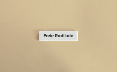 Freie Radikale auf weißer Buchstabenfliese vor beigem Hintergrund