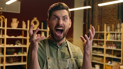 Crazy laughing shocked Caucasian man small business owner craftsman businessman potter crock male looking at camera laughing screaming emotion reaction shouting yell madness indoors pottery workshop
