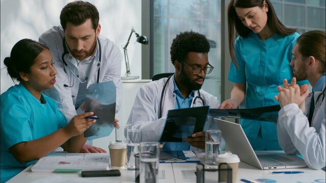 Multiethnic doctors medical diagnostic team meeting heath research xray analyzing African men Indian Caucasian women diverse nurse surgeon medicare five people talk discuss checkup results at clinic - Powered by Adobe