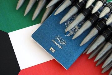 Kuwaiti passport and rifle bullets on flag. The concept of warfare and gun selling