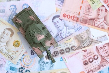 Thai baht currency money bills and toy tank. The concept of army funds and weapons sales