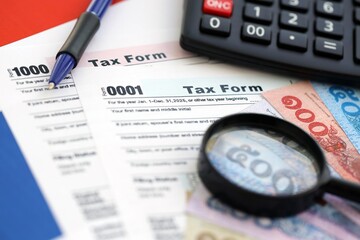 Thai baht money bills and calculator with tax form on flag. Taxation and accounting concept