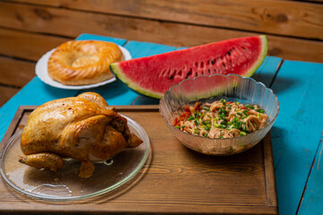 Udon noodles with saut ed vegetables in teriyaki sauce and spices, grilled whole chicken, and a slice of watermelon
