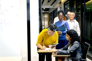 Fototapeta premium Businesspeople in line check in arriving at conference register desk. Asian senior audience and other queue up to register at reception. Attendees fill out information before attending seminar meeting