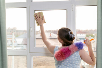 Young woman cleaning window with microfiber cloth. Housework concept