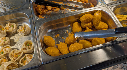 fried crab claws and steel trays full of hot cooked food in a self service restaurant