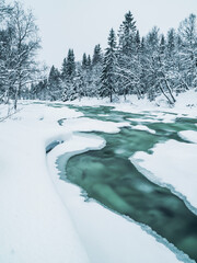 Frozen river flows through snowy landscape in Sweden during winter season