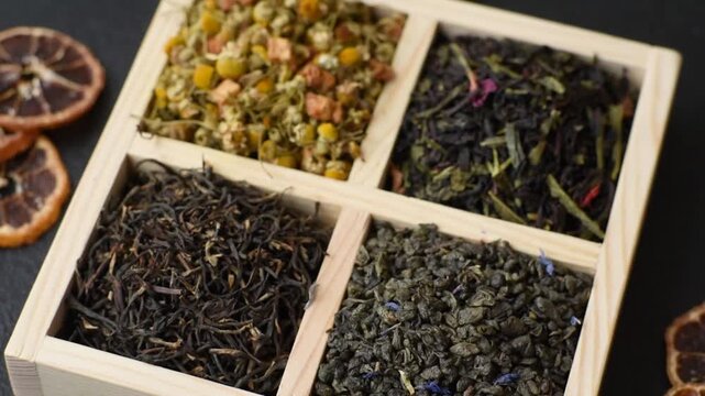 A wooden box with several types of dried tea, green, black, fruit, and chamomile. Dry tea in the box as a backdrop for your design.