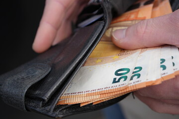 Paying or Saving: Man's Hands Withdrawing Money from a Purse