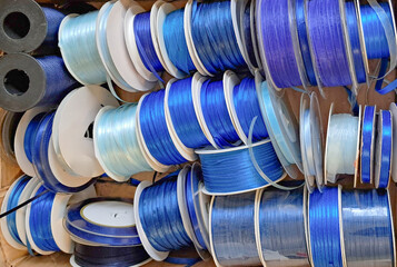 blue and light blue ribbon rolls arranged in a box for crafting and decoration