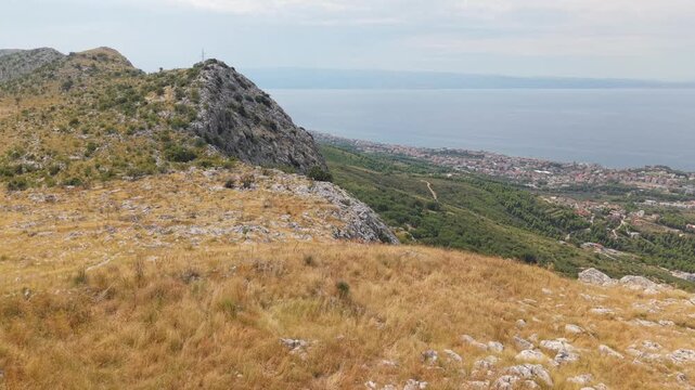 Ancient stone chapel on a coastal mountain ridge with panoramic sea view of the Dalmatian coast.