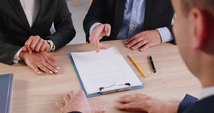 Couple sitting at the desk in a meeting with lawyer discussing and refusing to sign papers documents or divorce. Business people refusing to sign contract. 4k video. Slow motion video.
